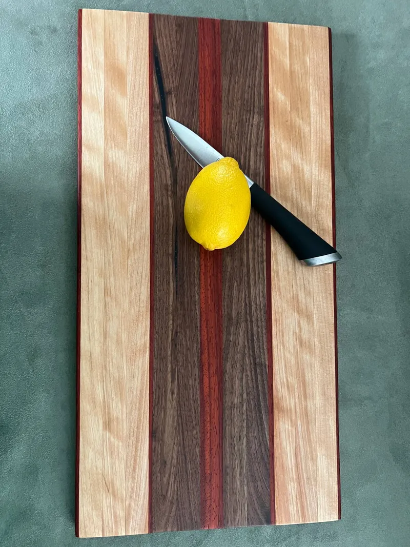 Medium cutting board with yellow birch outer strips, a walnut center and red padauk stripes, shown straight on